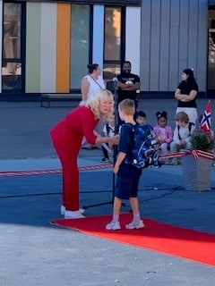 en person og et barn på en rød matte foran en folkemengde