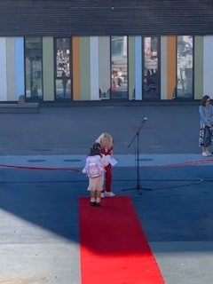 en person og et barn på en rød matte foran en bygning