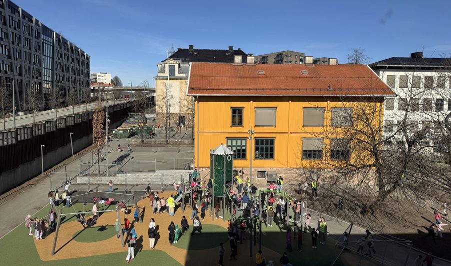 en gruppe mennesker som går rundt i en gårdsplass med bygninger i bakgrunnen