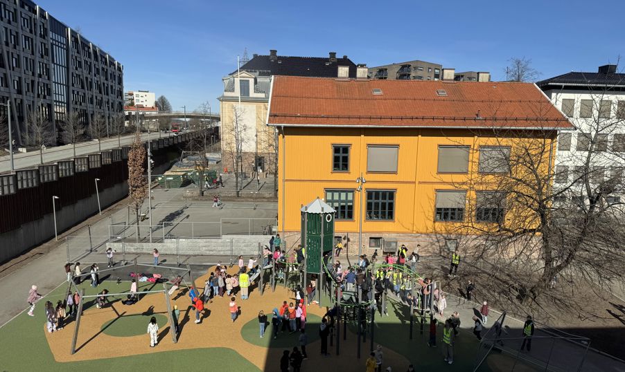 en gruppe mennesker som går rundt i en gårdsplass med bygninger i bakgrunnen